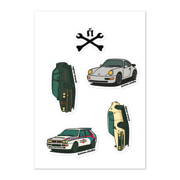 Ñom Studio Racing Development kiss-cut sticker sheet featuring a wrench-and-ñ mark and illustrated classic sports and rally cars, including a Porsche 911 and a Martini-liveried Lancia Delta